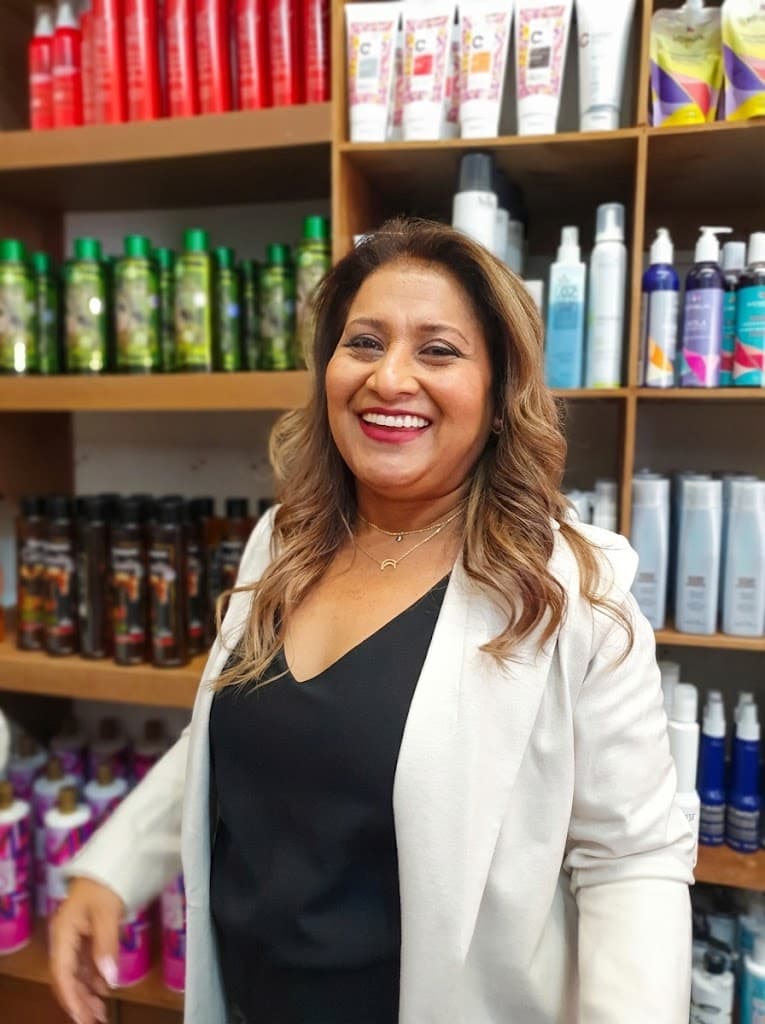 Fundadora de Distribuidora Sicarú sonriendo frente a estantes de productos profesionales de belleza