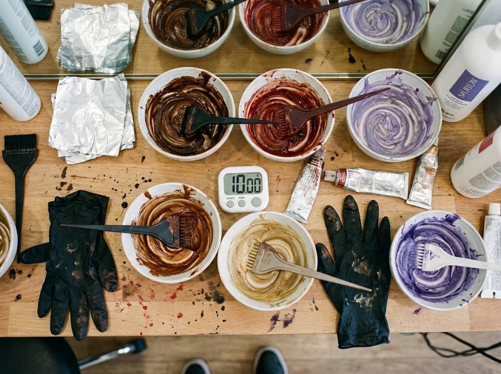 Vista cenital de mezclas de tintes profesionales de diferentes colores con brochas y herramientas de colorista