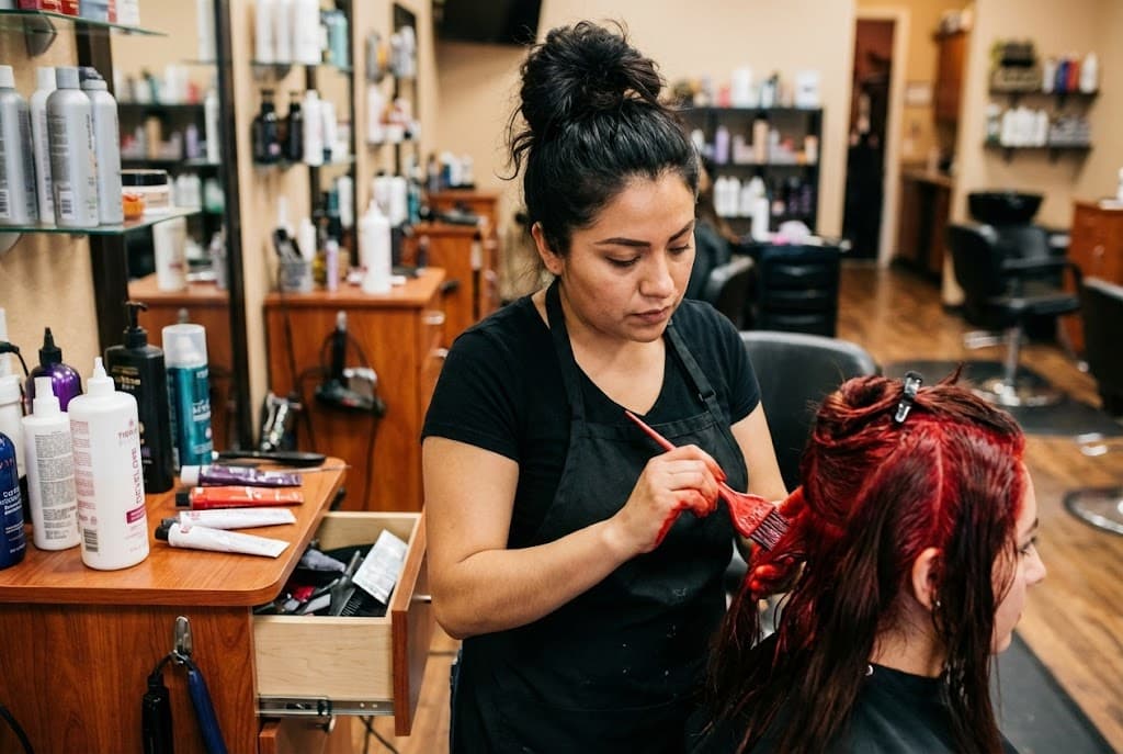 Estilista profesional aplicando tinte rojo a clienta en salón de belleza
