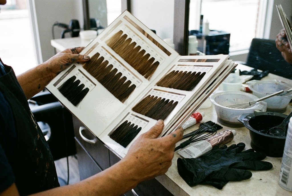 Colorista profesional consultando muestrario de tonos de tinte con herramientas de mezcla para coloración